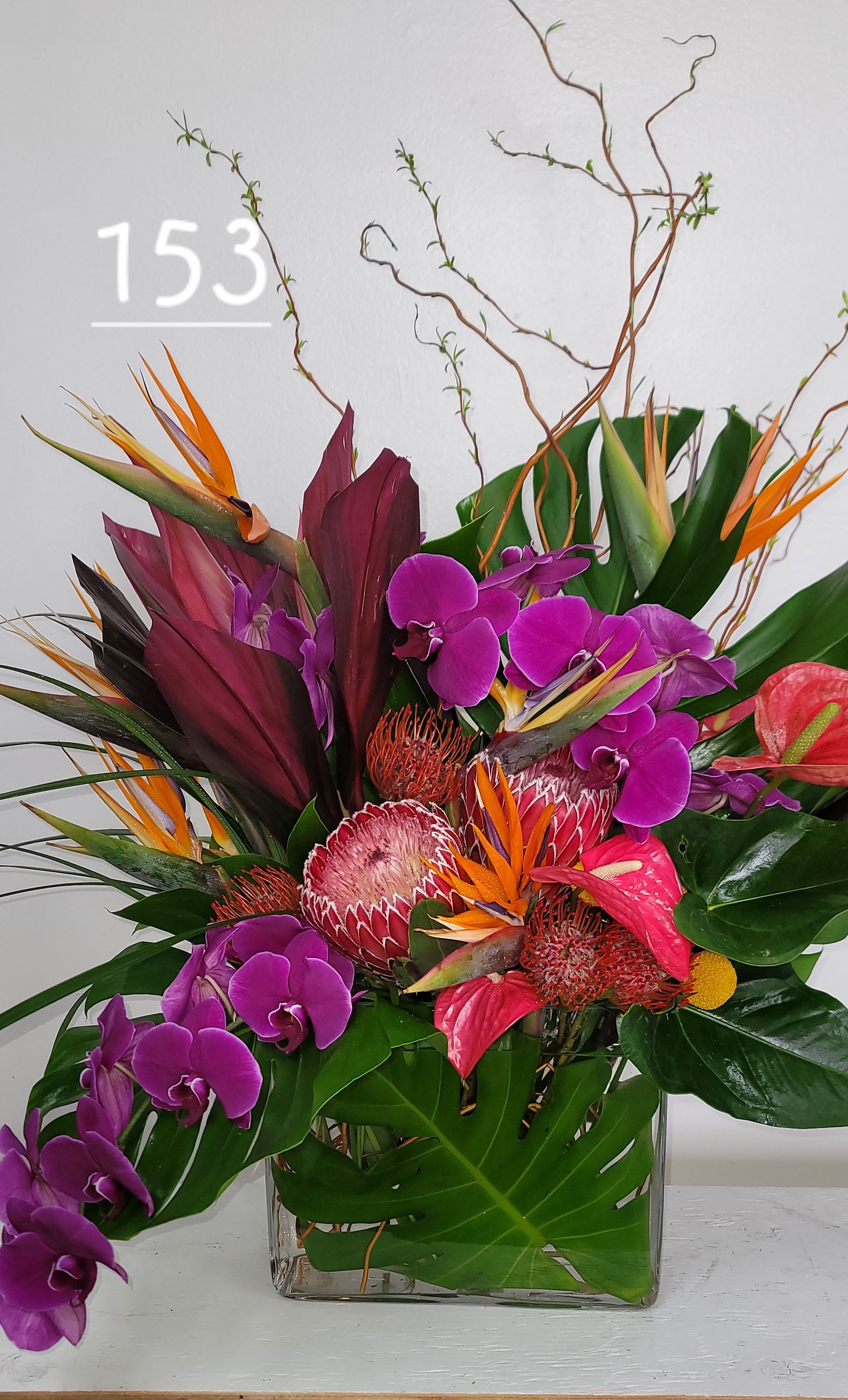 A vase filled with flowers and leaves with the number 153 on it