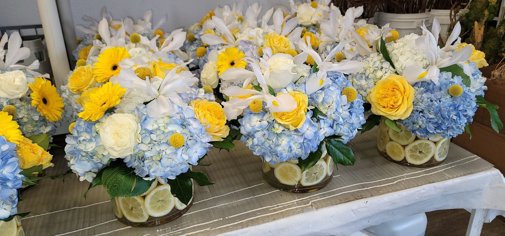 A table topped with vases filled with blue and yellow flowers.