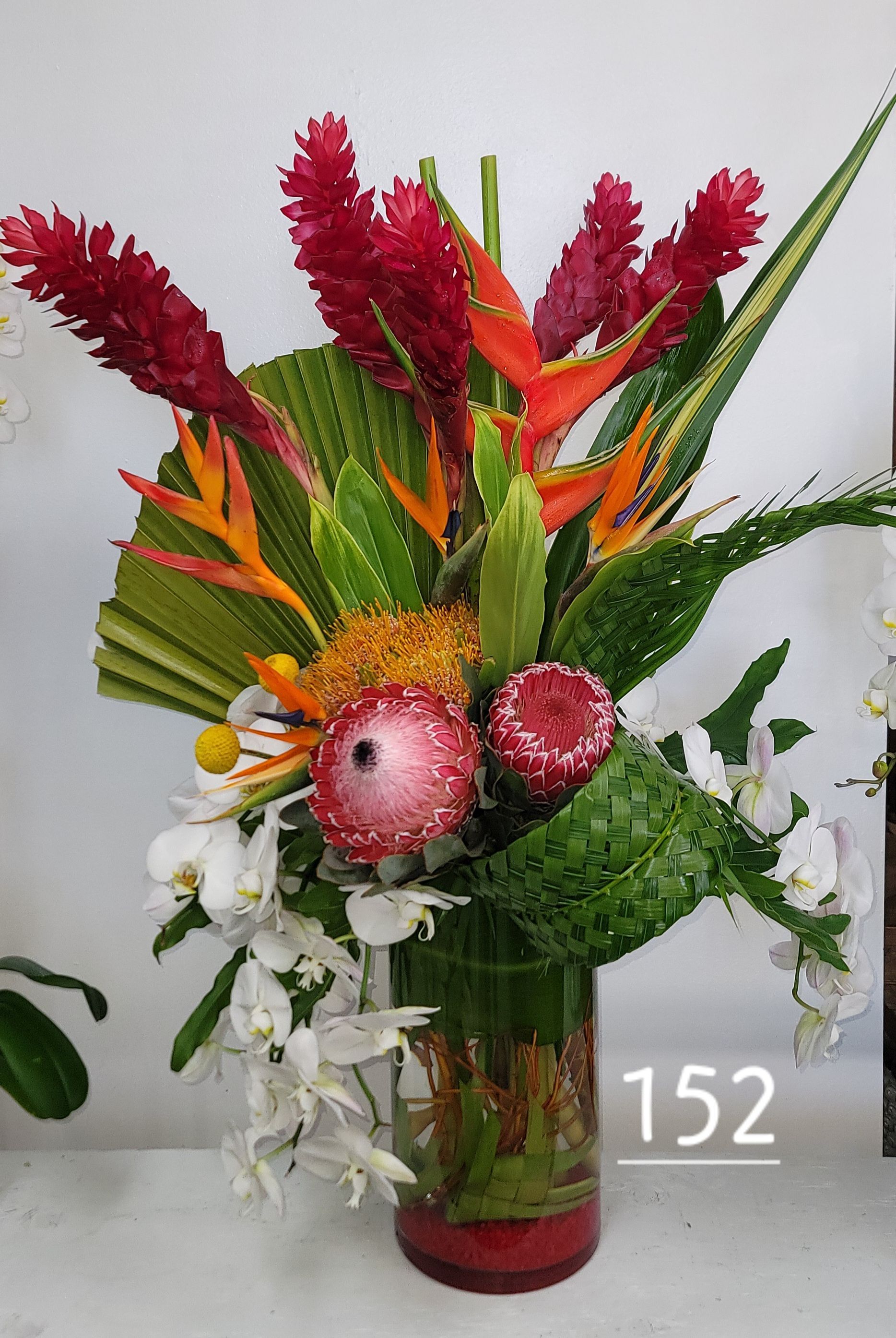 A vase filled with flowers and leaves with the number 152 on it.