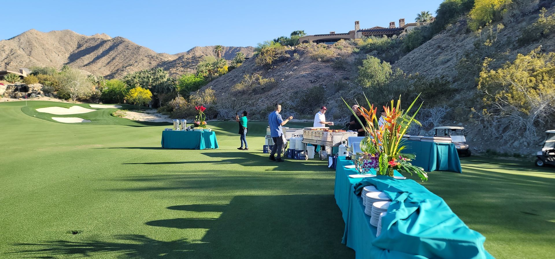 A group of people are standing around tables on a golf course.