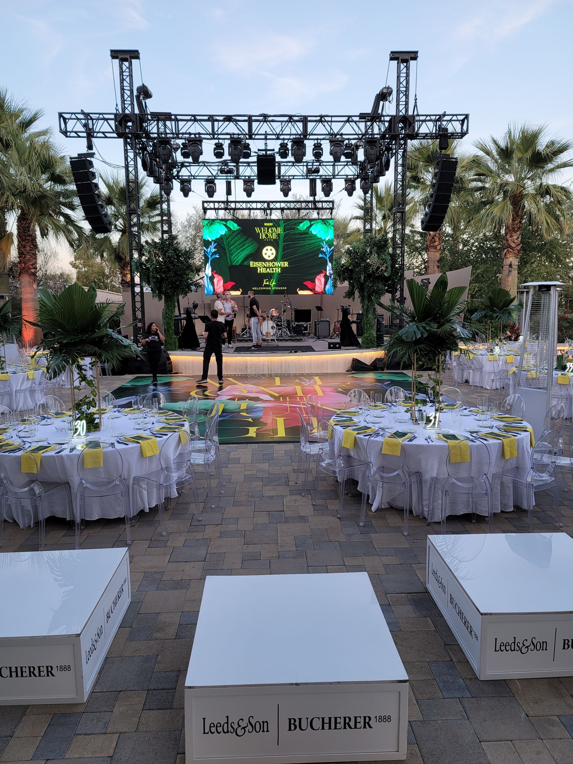 A large screen is behind a stage with tables and chairs set up for a party.