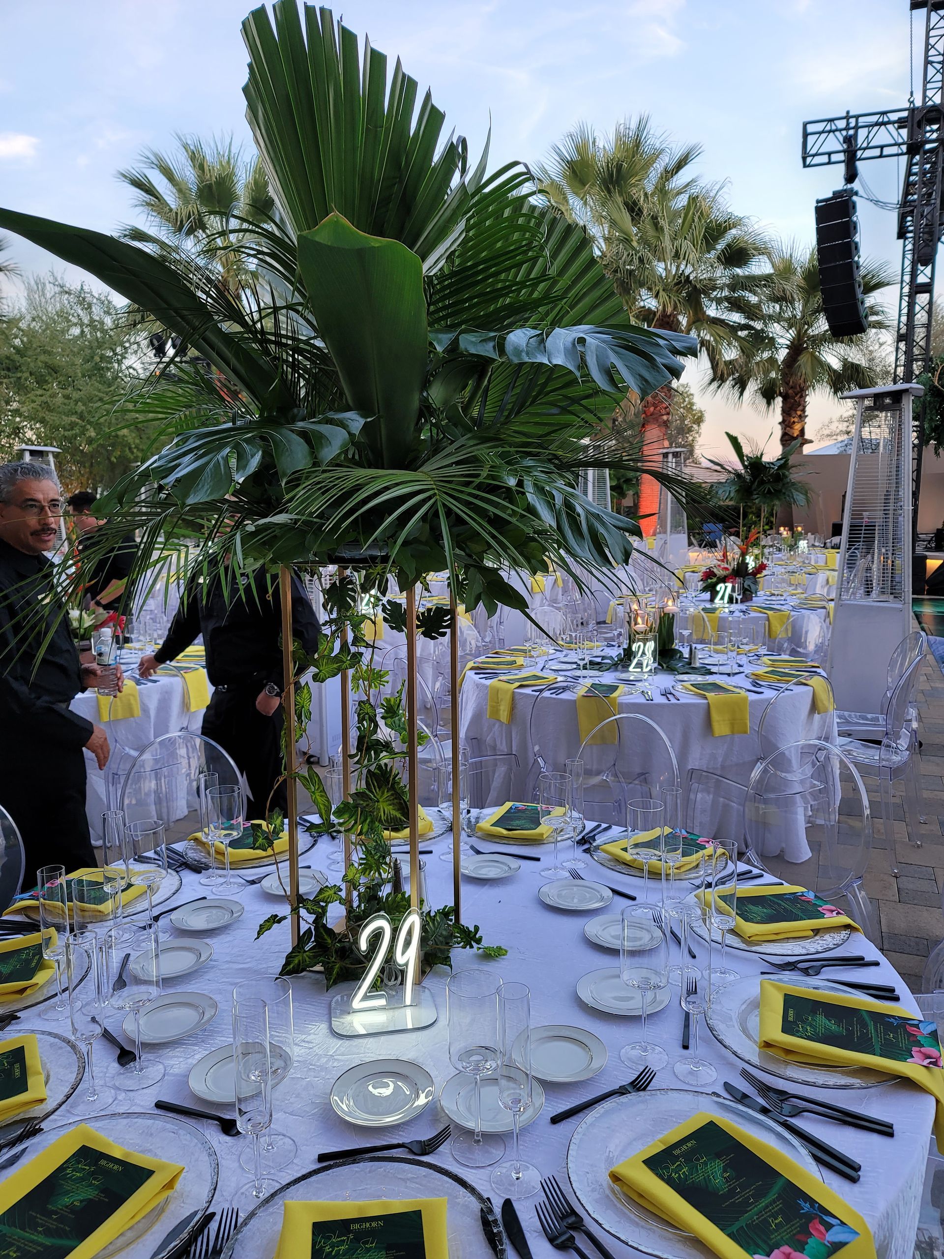 A table set for a wedding reception with a palm tree in the center.