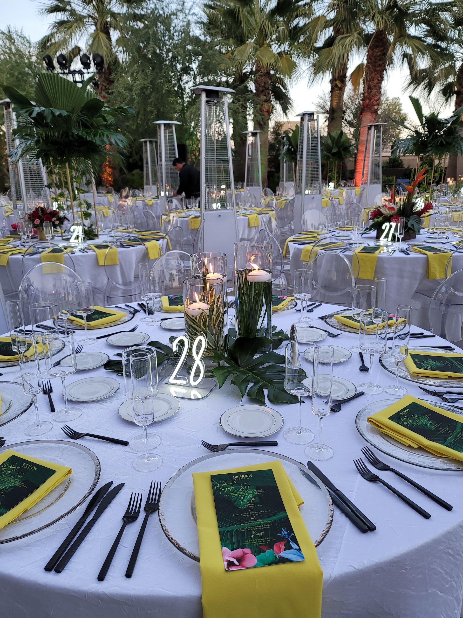 A table set for a wedding reception with plates , utensils , and candles.