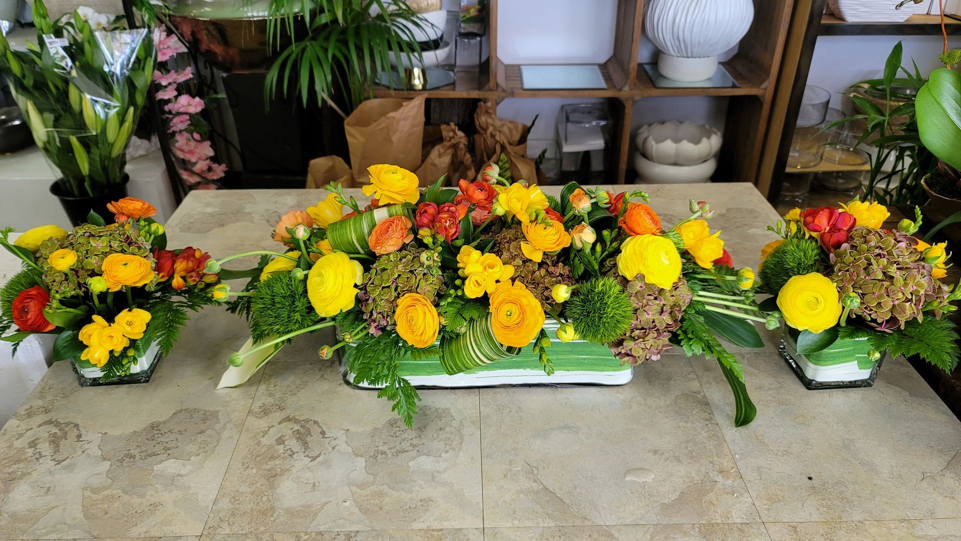 A table with three vases of flowers on it.
