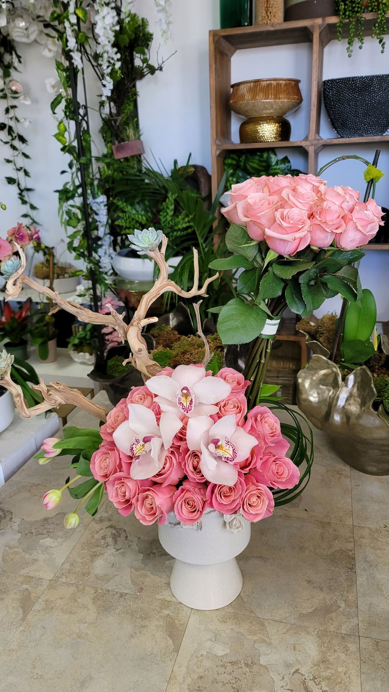 A vase filled with pink roses and orchids is sitting on a table.