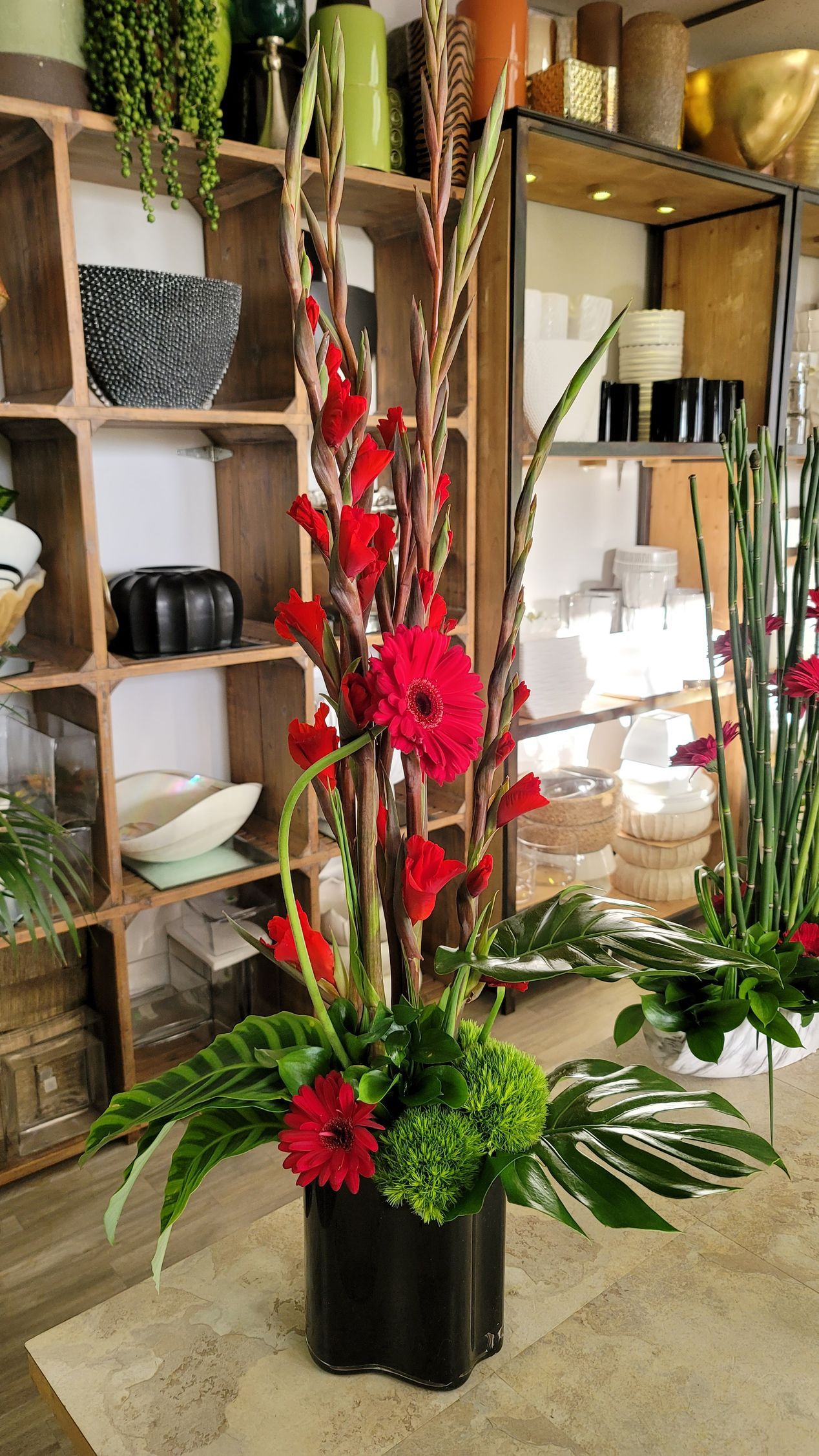 A vase filled with red flowers and greenery is sitting on a table in a room.