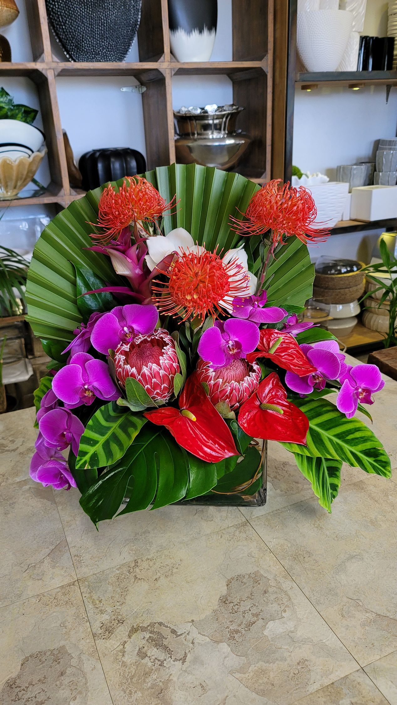 A vase filled with flowers and leaves is sitting on a table.