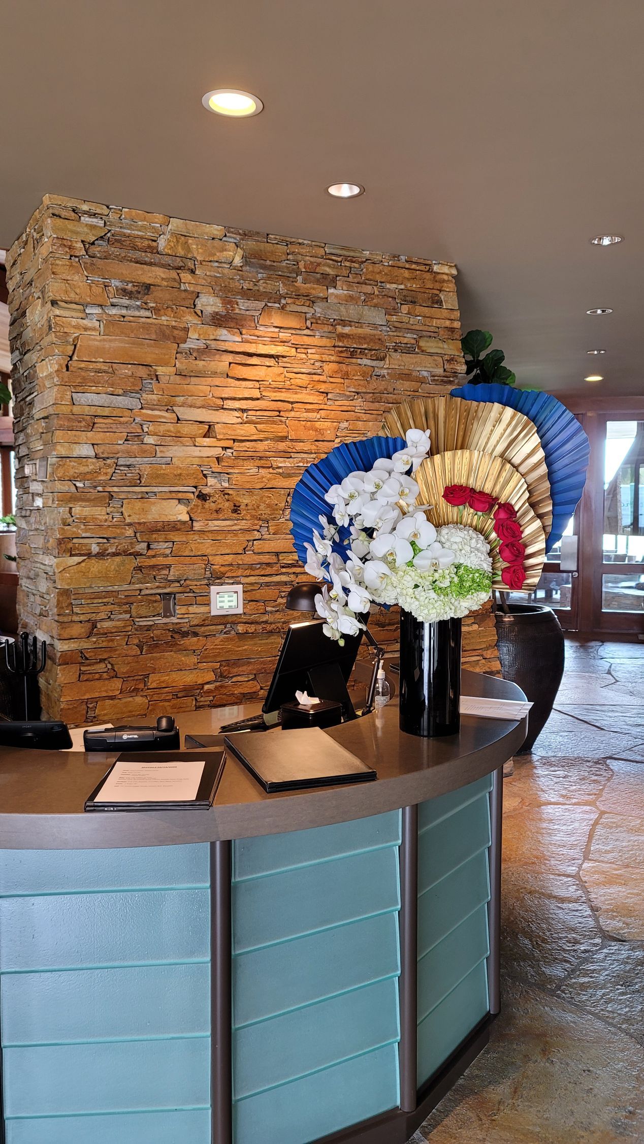 A reception desk with flowers and fans on it in a room with a brick wall.