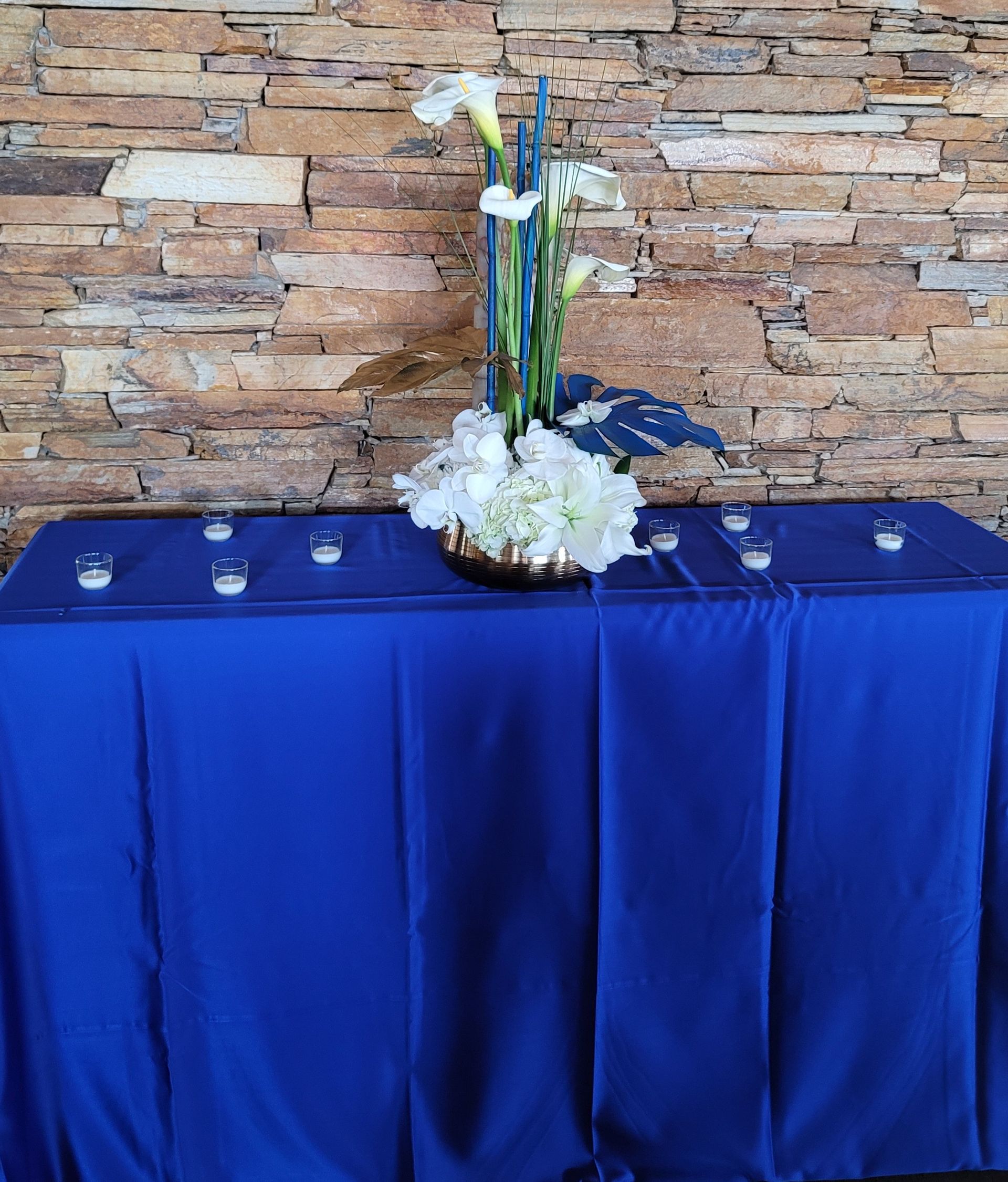 A table with a blue table cloth and a vase of flowers on it