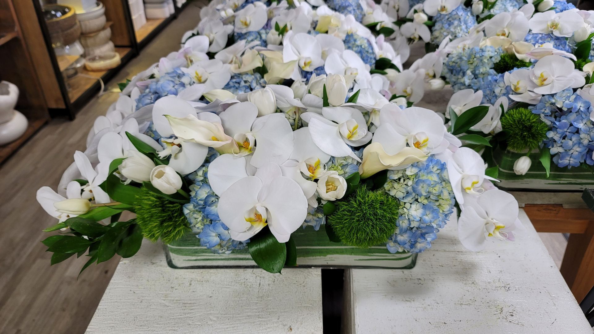 A vase filled with white and blue flowers is sitting on a table.