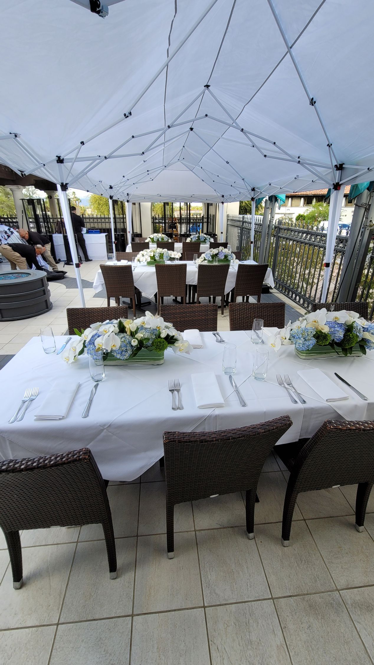 A table and chairs are set up under a tent for a wedding reception.