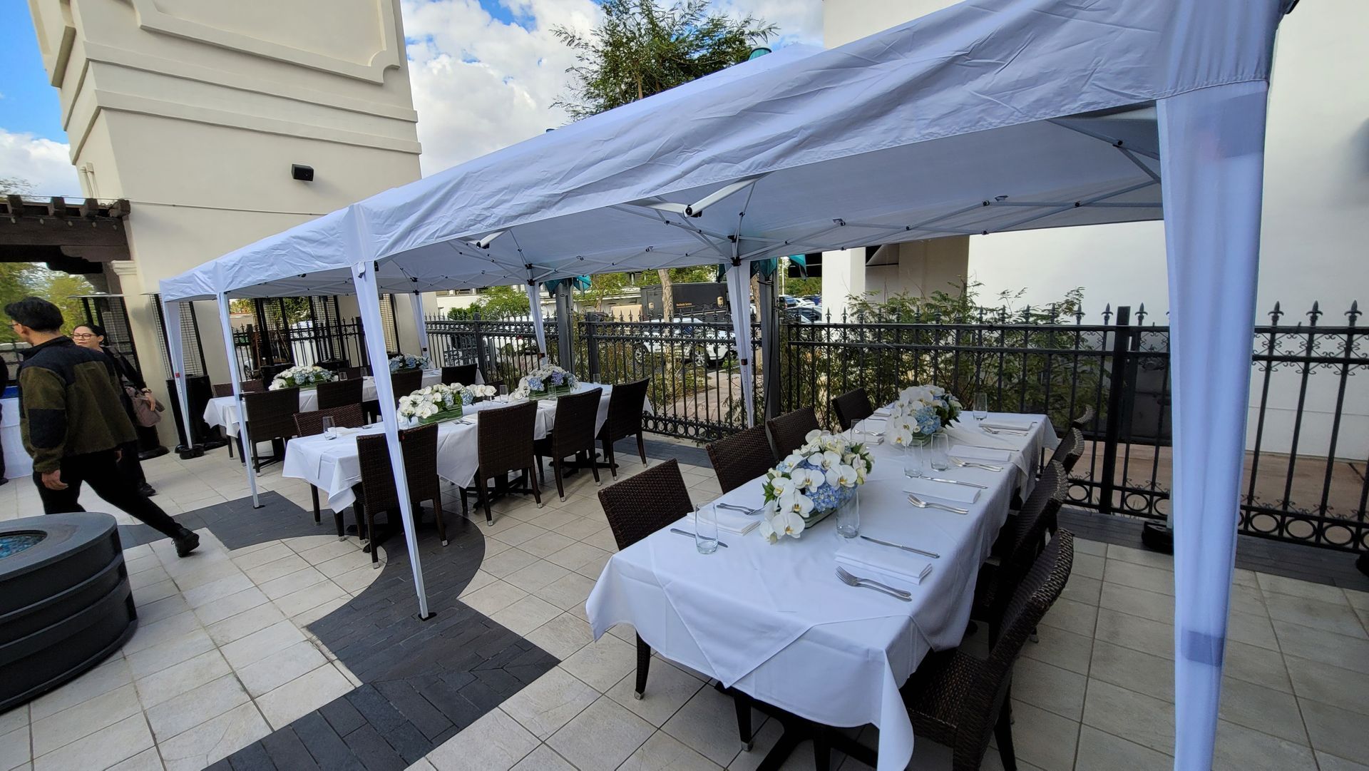 A patio with tables and chairs under a white tent.
