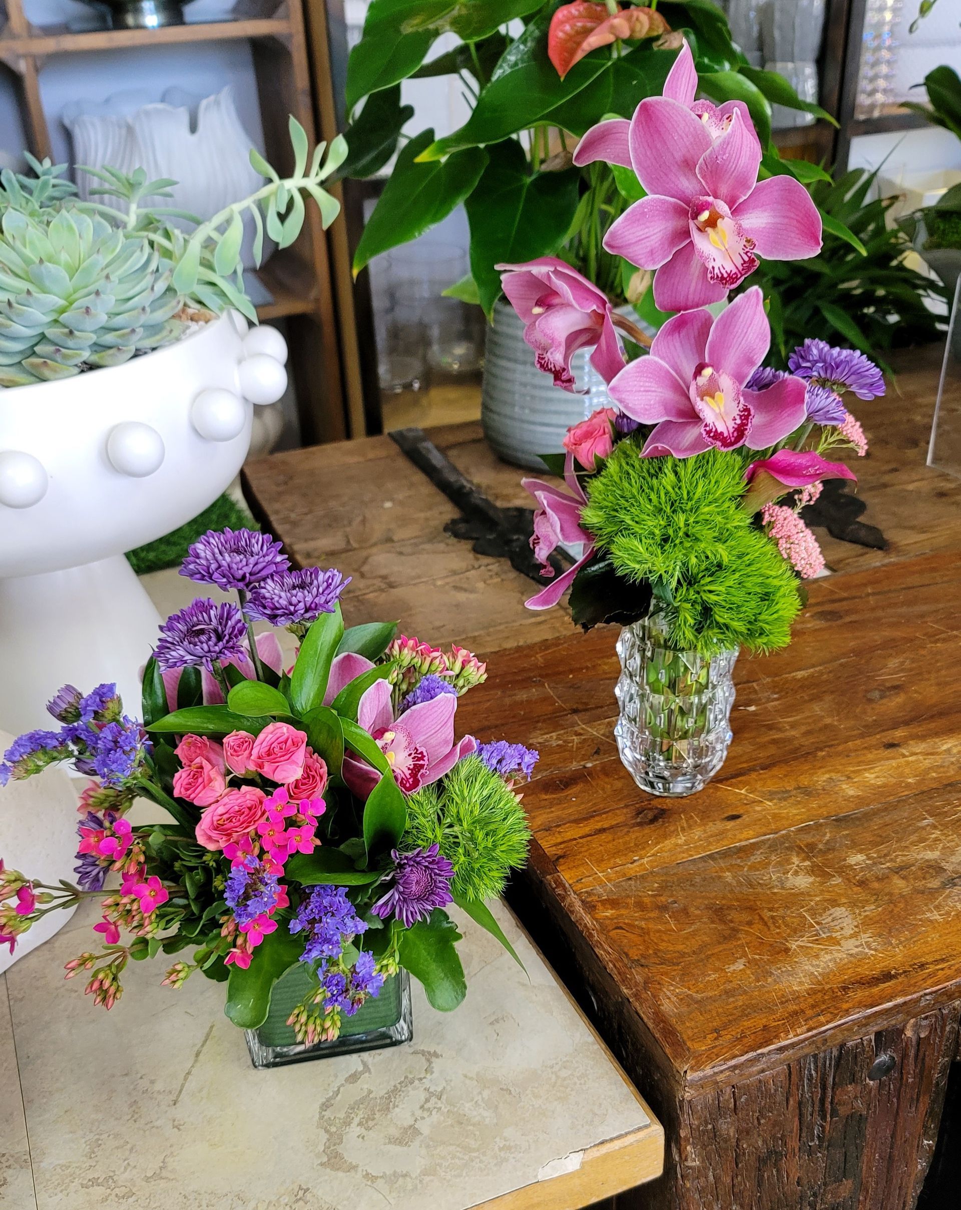 Two vases of flowers are sitting on a wooden table.