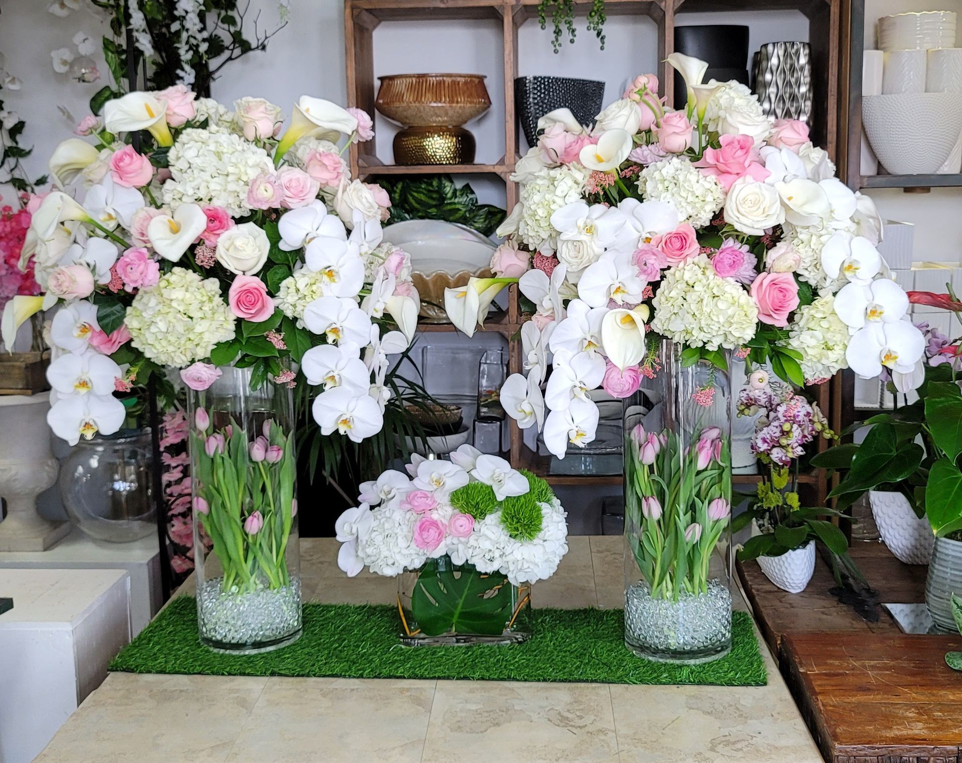 Two vases filled with pink and white flowers are on a table