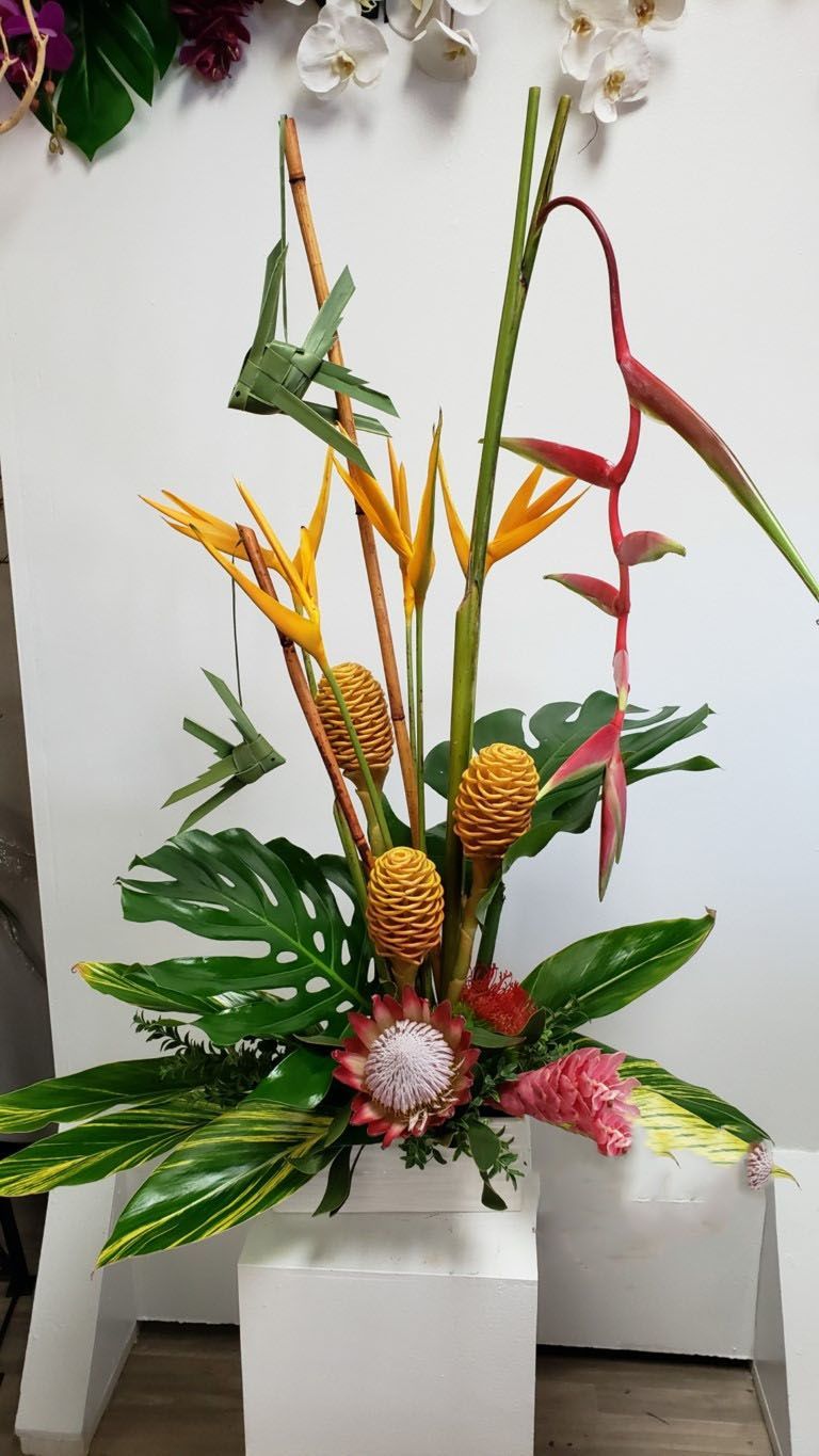 A vase filled with flowers and pineapples is sitting on a table.