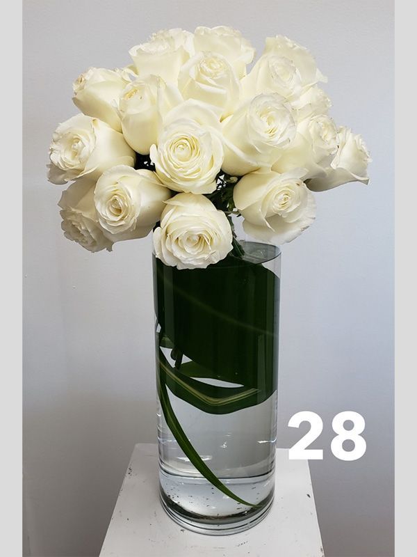 A vase filled with white roses is sitting on a table.