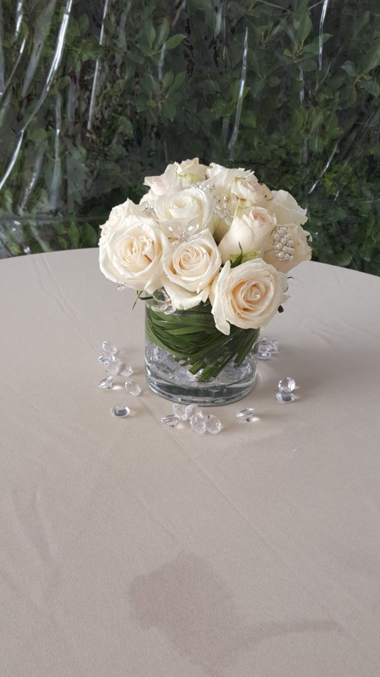A vase filled with white roses is sitting on a table.