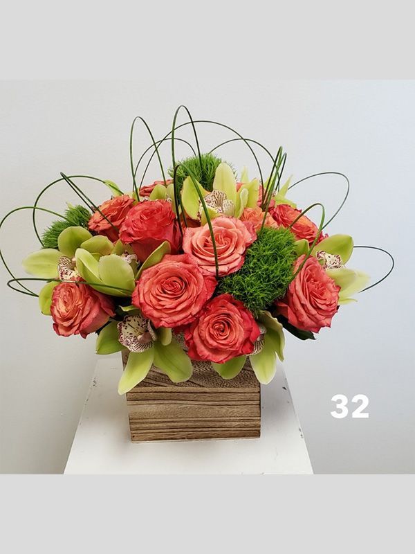 A wooden box filled with red roses and greenery