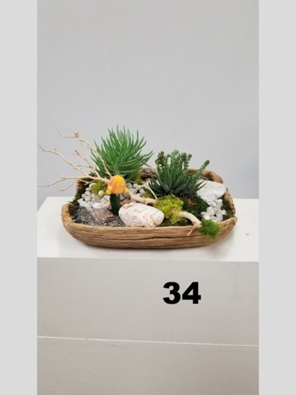 A basket filled with plants and rocks is sitting on top of a white table.