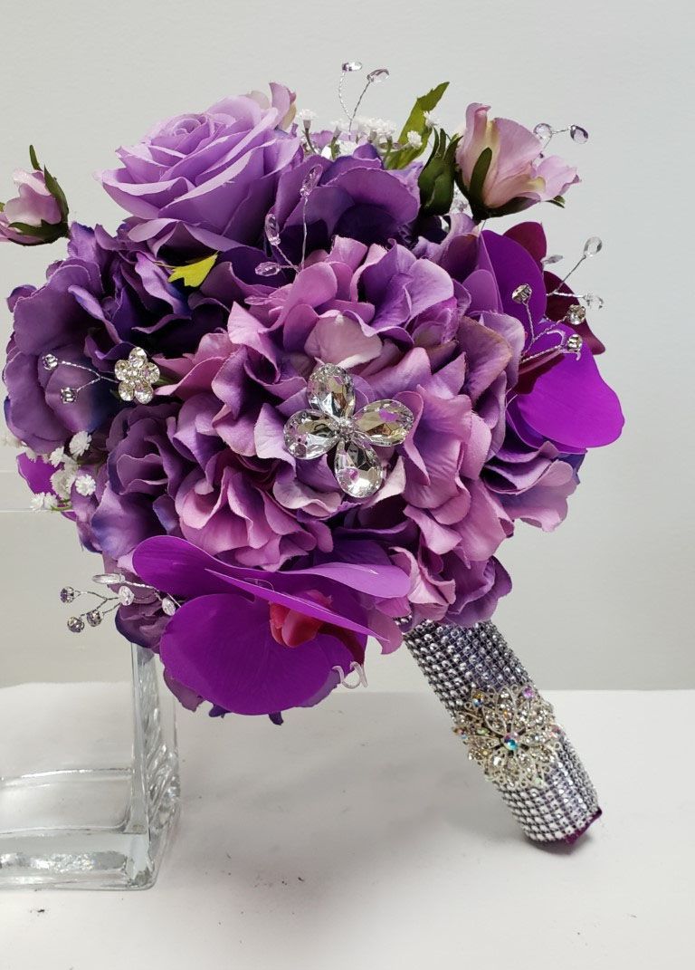 A bouquet of purple flowers with rhinestones on the handle