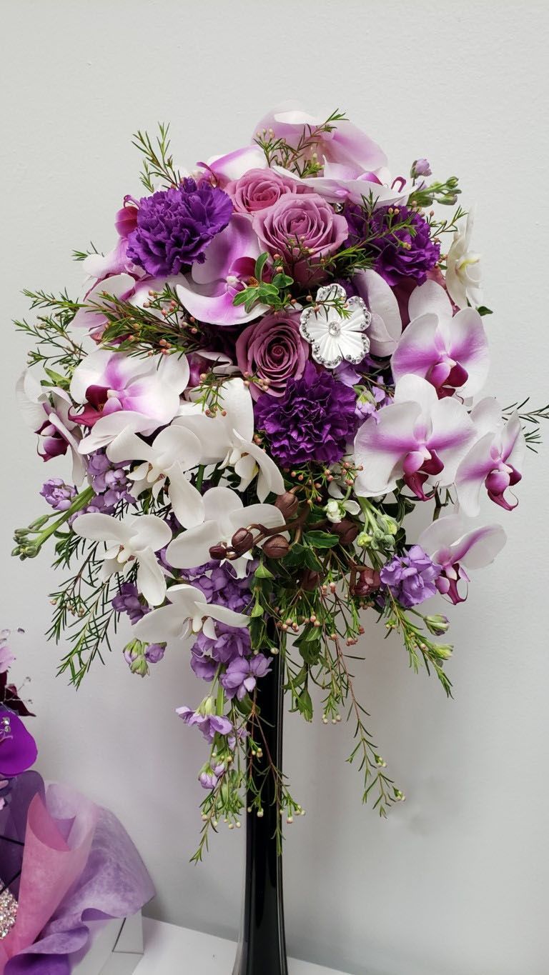 A vase filled with purple and white flowers is sitting on a table.