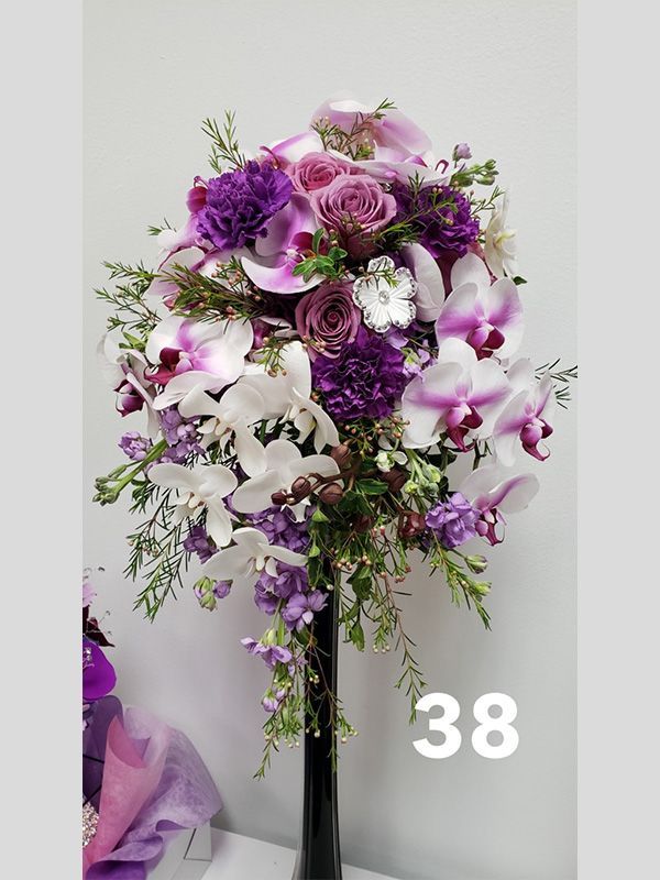 A vase filled with purple and white flowers has the number 38 on it