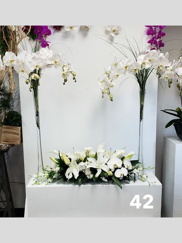 A bunch of white flowers in vases on a table with the number 42 on it.