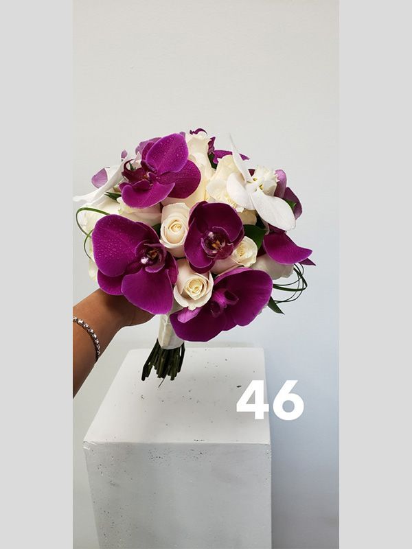 A person is holding a bouquet of purple and white flowers