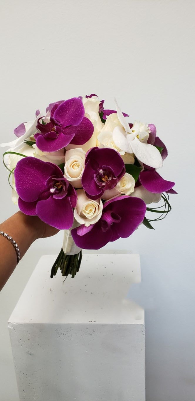 A person is holding a bouquet of purple and white flowers.