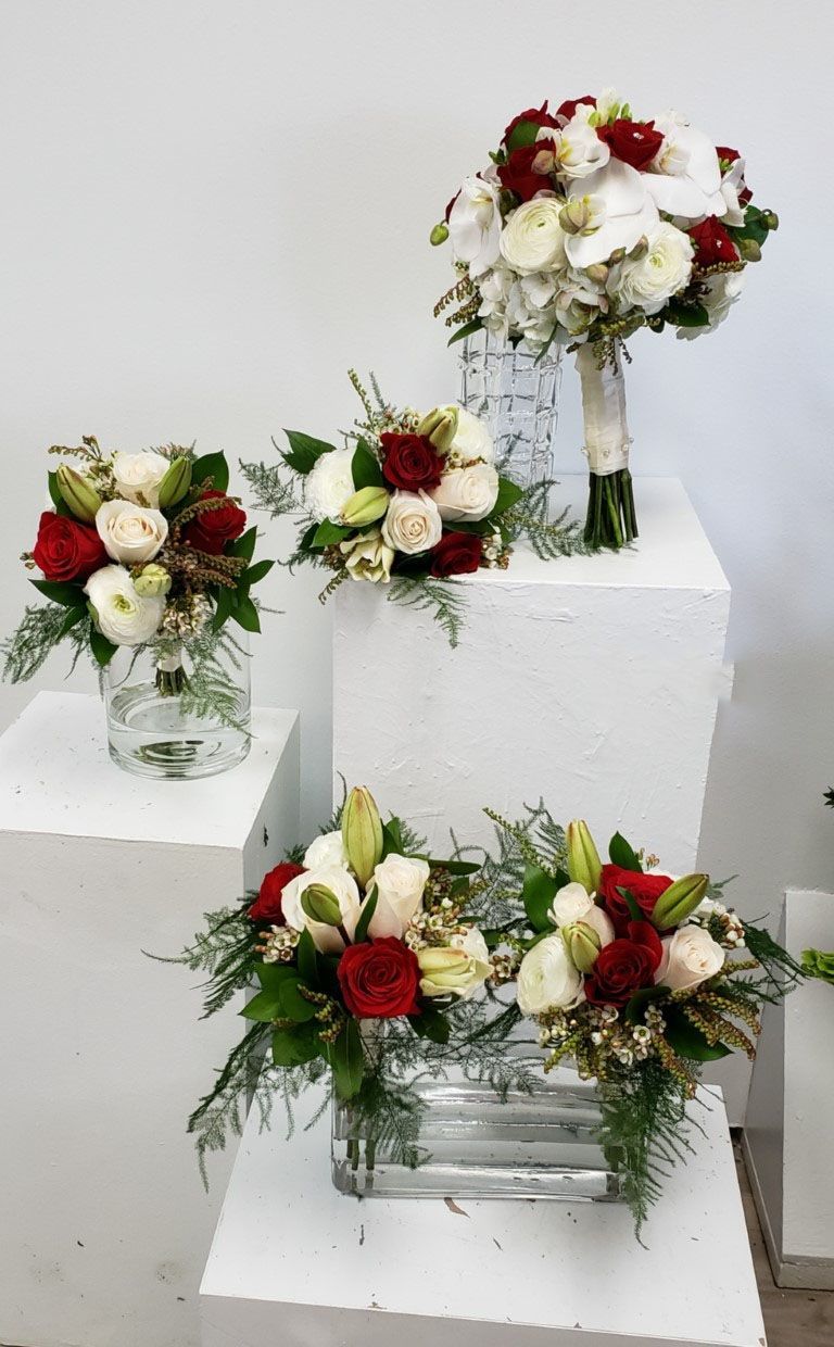 Three vases filled with red and white flowers are sitting on a table.