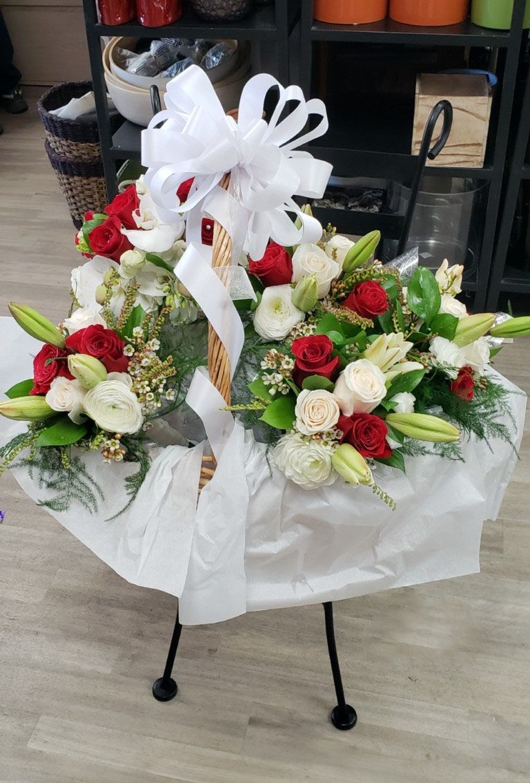 A basket filled with red and white flowers is sitting on a table.