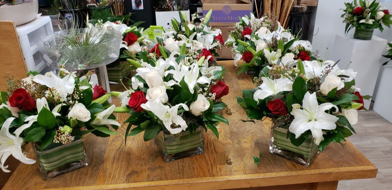 A table topped with vases filled with white and red flowers.