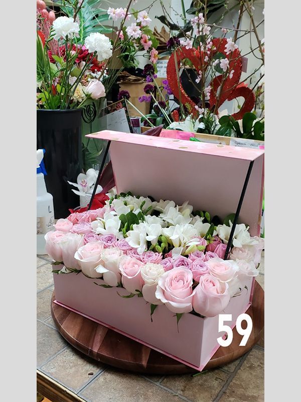 A pink box filled with pink and white roses is sitting on a table.