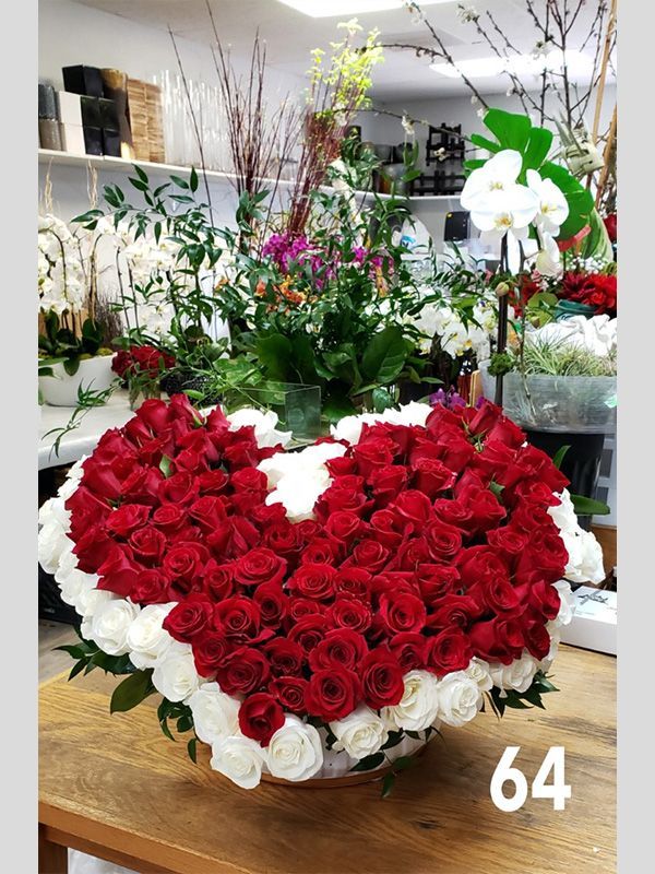 A large heart shaped vase filled with red and white roses.