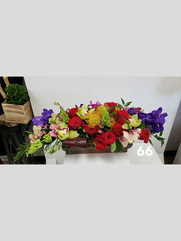 A long vase filled with flowers is sitting on a table.