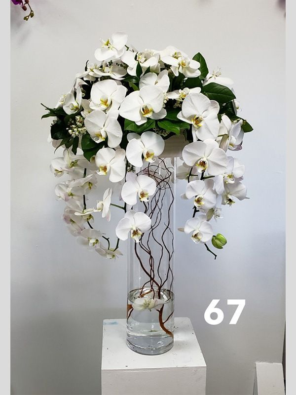 A vase filled with white flowers and the number 67 on the bottom