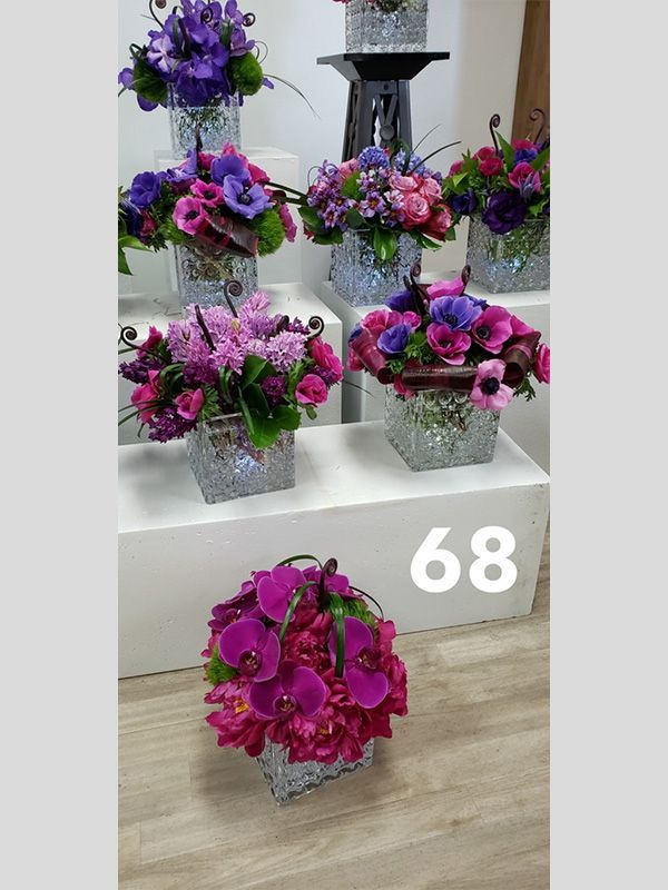A bunch of purple flowers in vases with the number 68 on the bottom