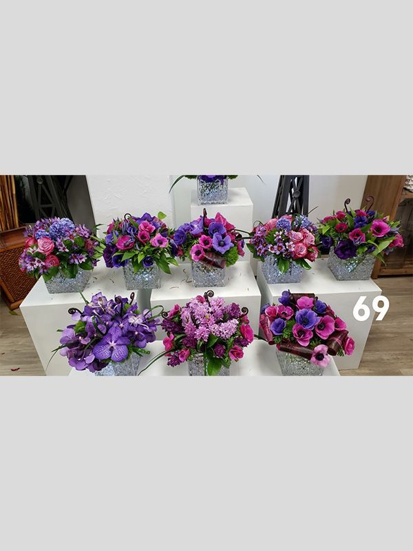A bunch of purple flowers in baskets on a table.