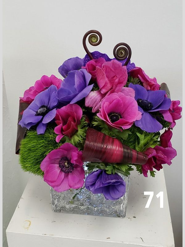 A vase filled with pink and purple flowers is sitting on a table.