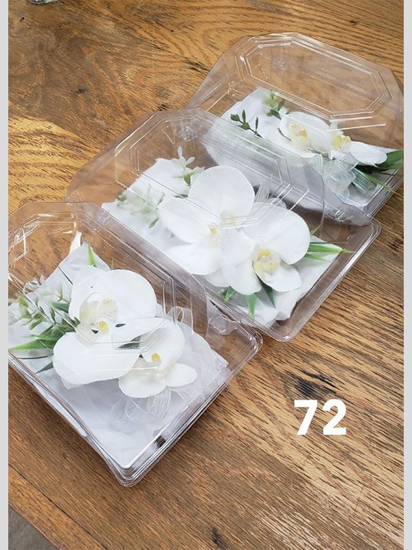 Two plastic containers filled with white flowers are sitting on a wooden table.