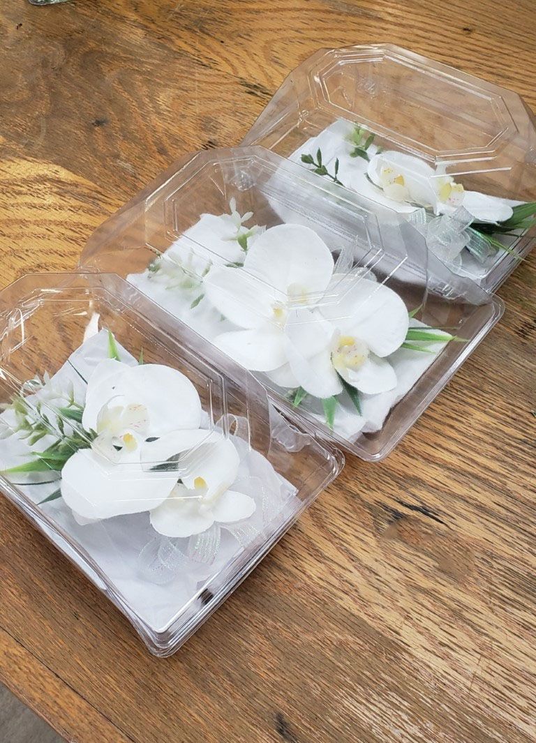 Two plastic containers filled with white flowers are sitting on a wooden table.