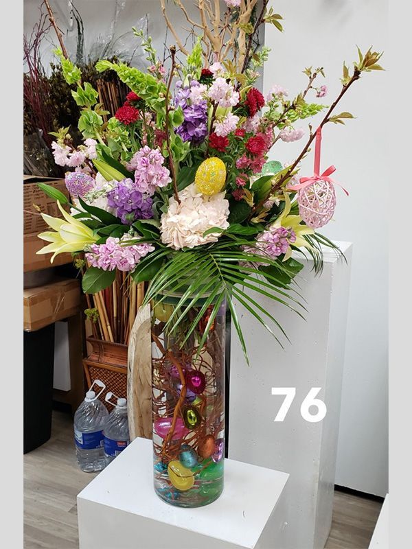 A vase filled with flowers and easter eggs on a table.