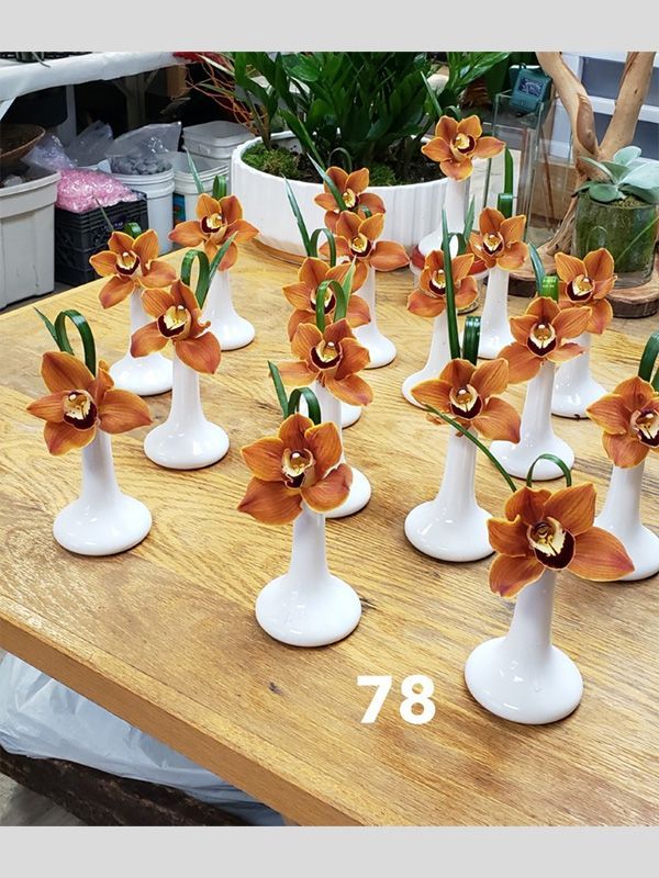 A table topped with a bunch of small vases with flowers in them.