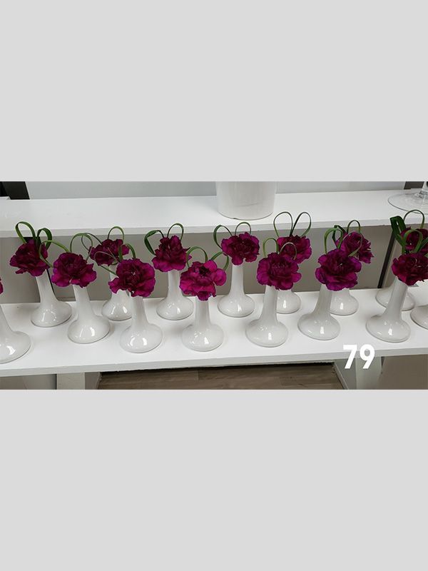 A row of white vases filled with purple flowers on a table.