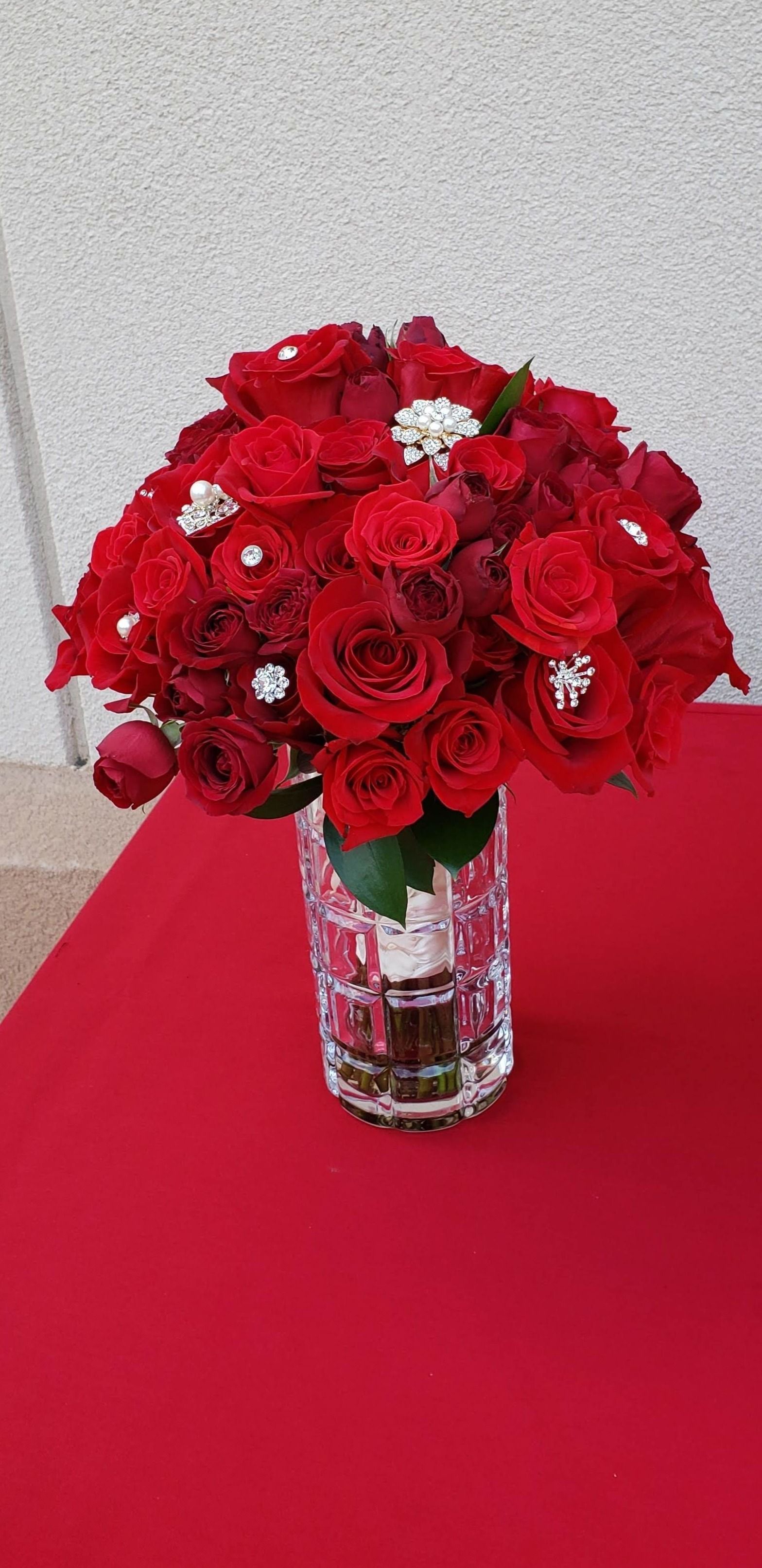 A vase filled with red roses is sitting on a red table.