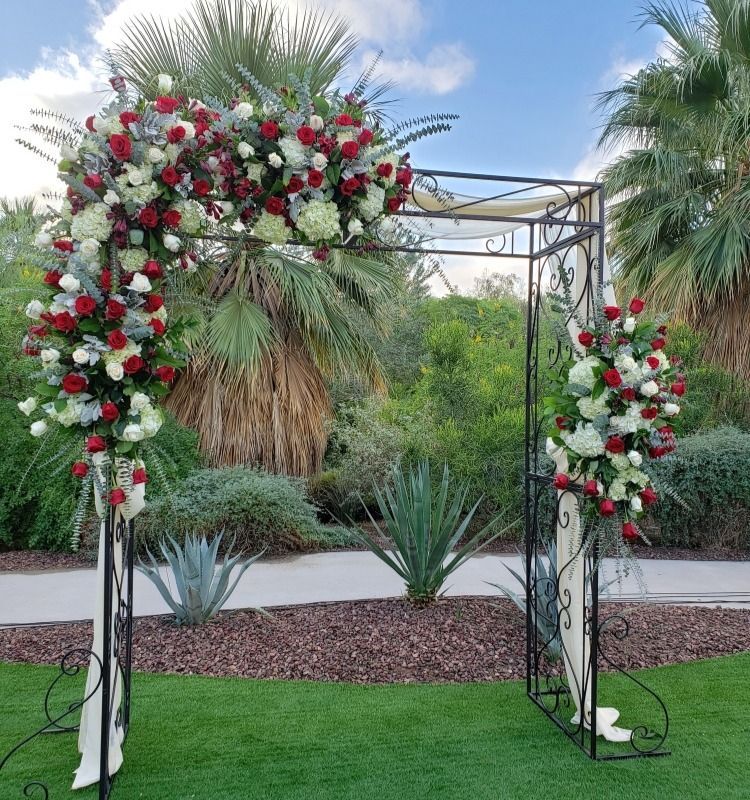 A wrought iron arch decorated with red and white flowers