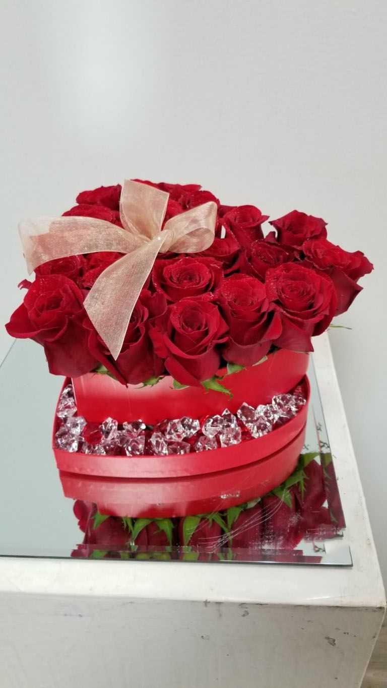 A heart shaped box filled with red roses and diamonds