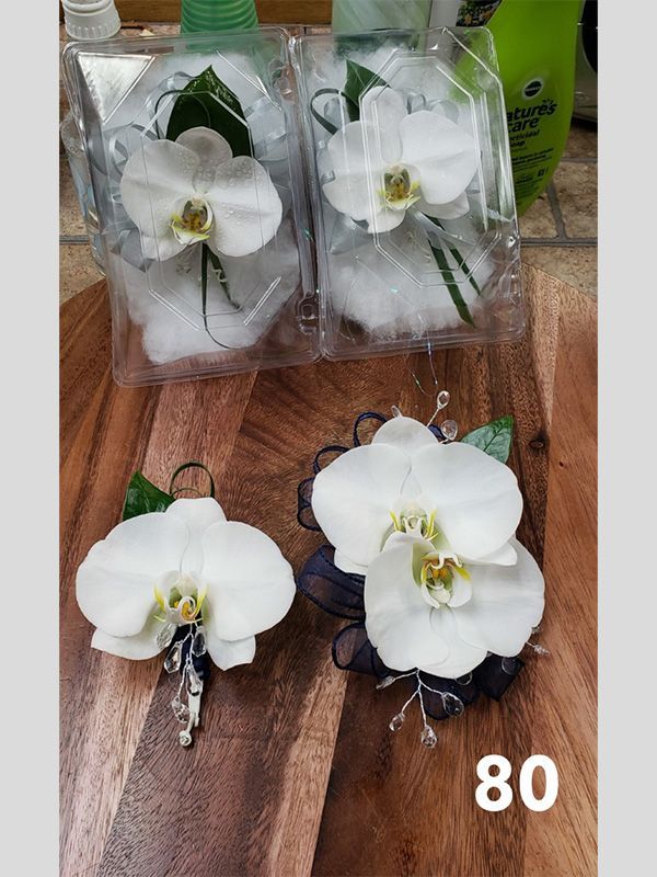 A couple of white flowers sitting on top of a wooden table.