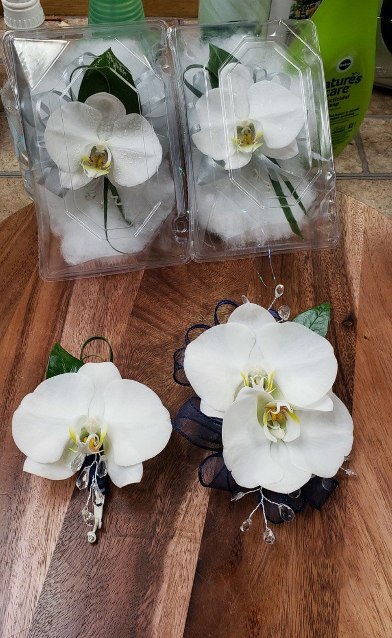 A couple of white orchids sitting on top of a wooden table.