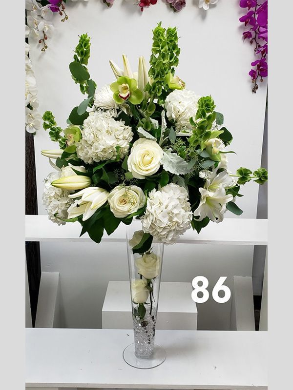 A vase filled with white flowers with the number 86 on the bottom